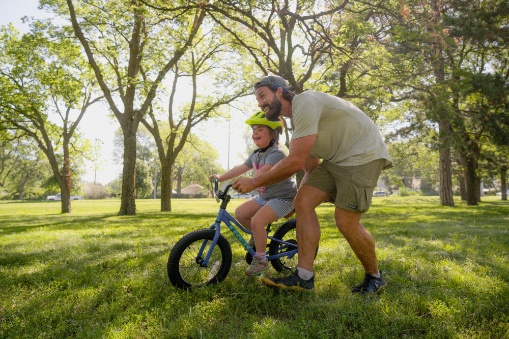 An Adventure For All coach helping a girl learn how to ride a bike.