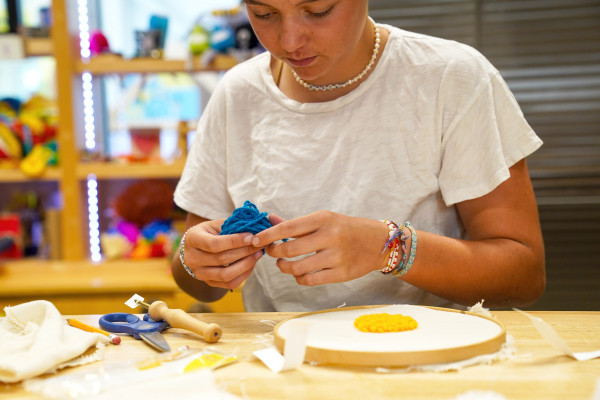 A teenage girl working on a needle punching project at the Amazeum.