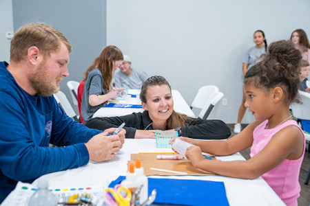 Girl and Father making paper craft activity with Amazeum team member