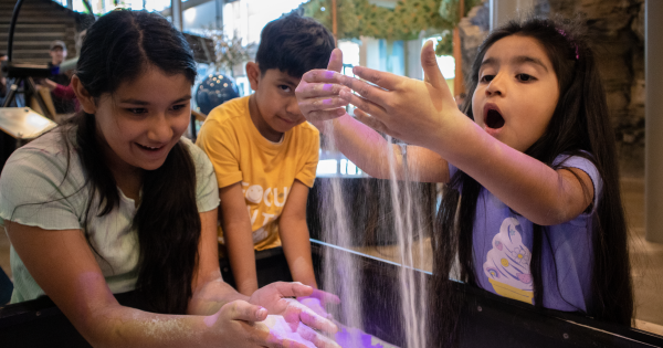 3 Children playing with sand in an exhibit